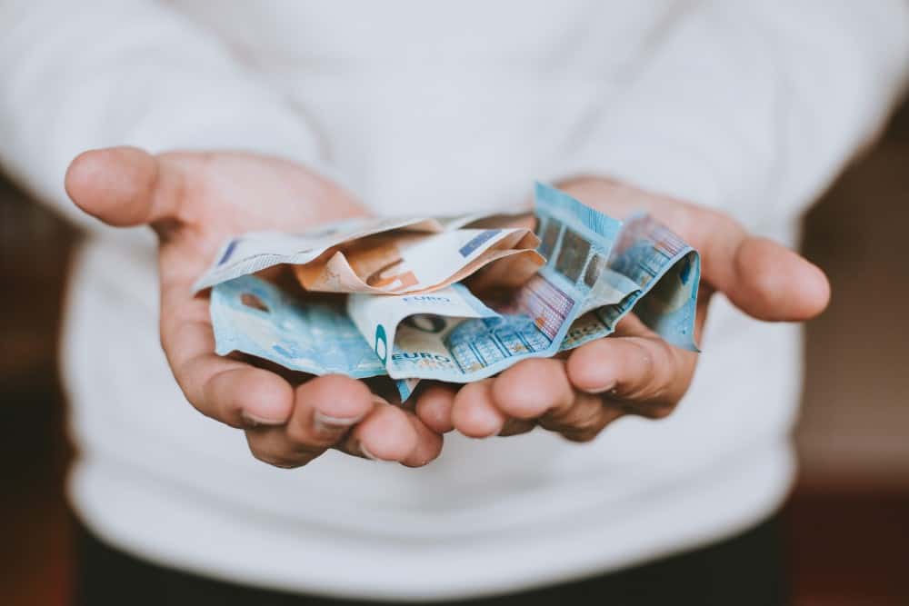 Die Hände einer Person halten einen Stapel Geld in der Hand, während sie Geld ins Ausland überweist.