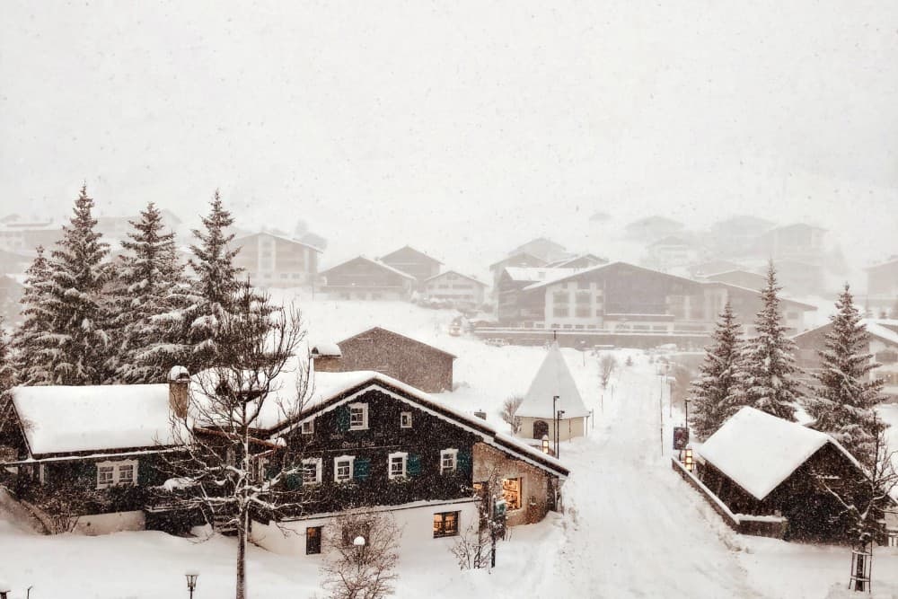 Ein österreichisches Dorf in den Alpen, mit Skigebieten und Schnee, der alles bedeckt.