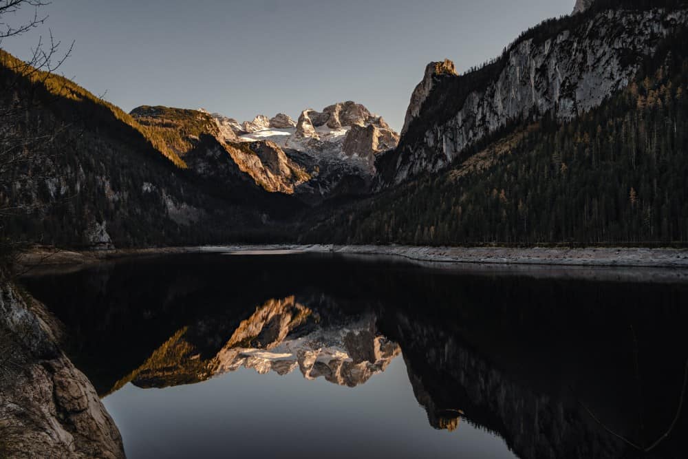 Ein wunderschöner See inmitten der Österreichischen Alpen, der die majestätischen Berge, die ihn umgeben, perfekt widerspiegelt.